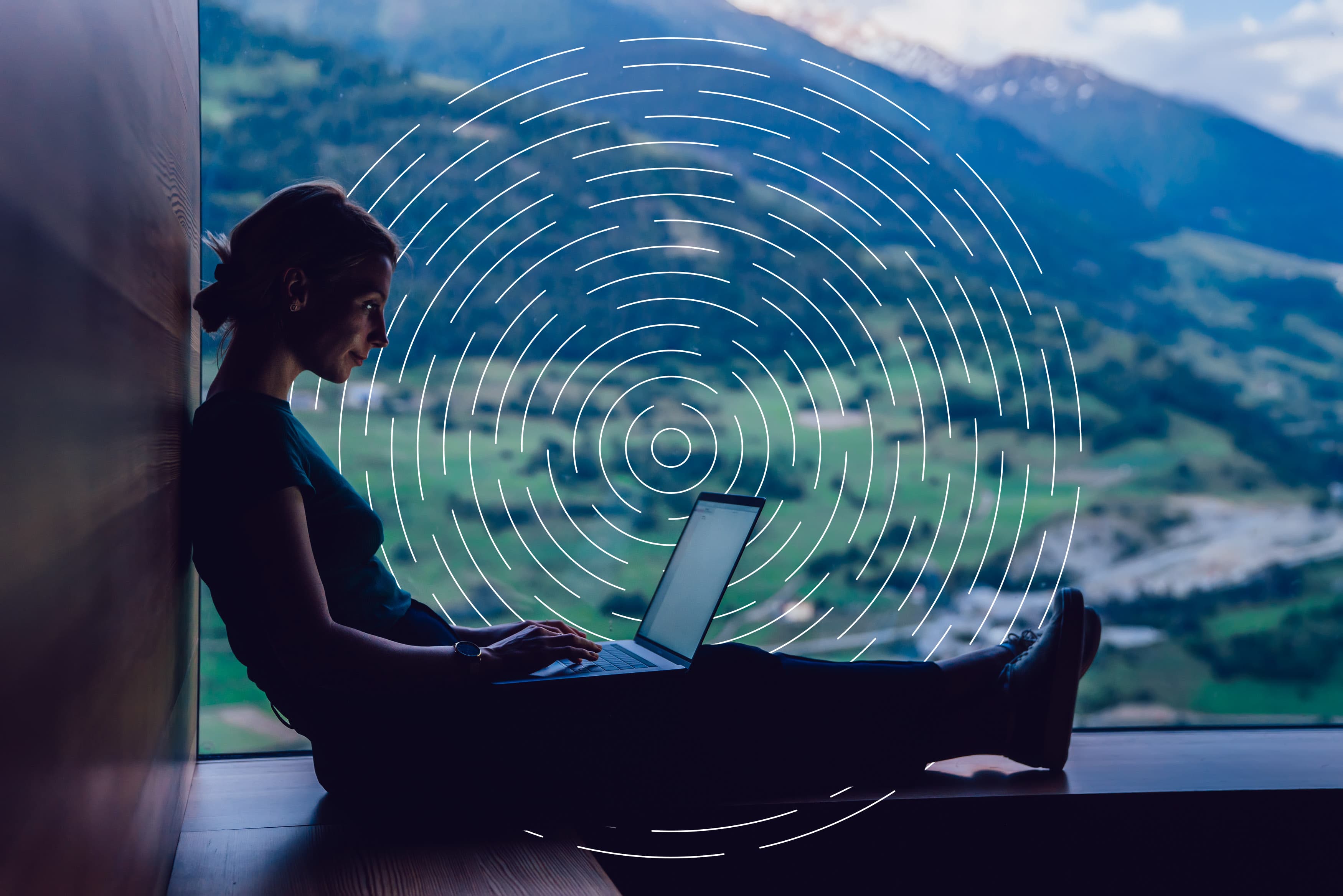 woman sitting with laptop with hills in the background