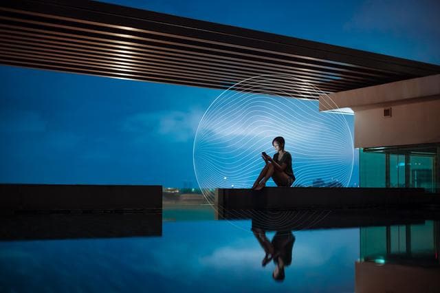 person sitting looking at phone next to pool
