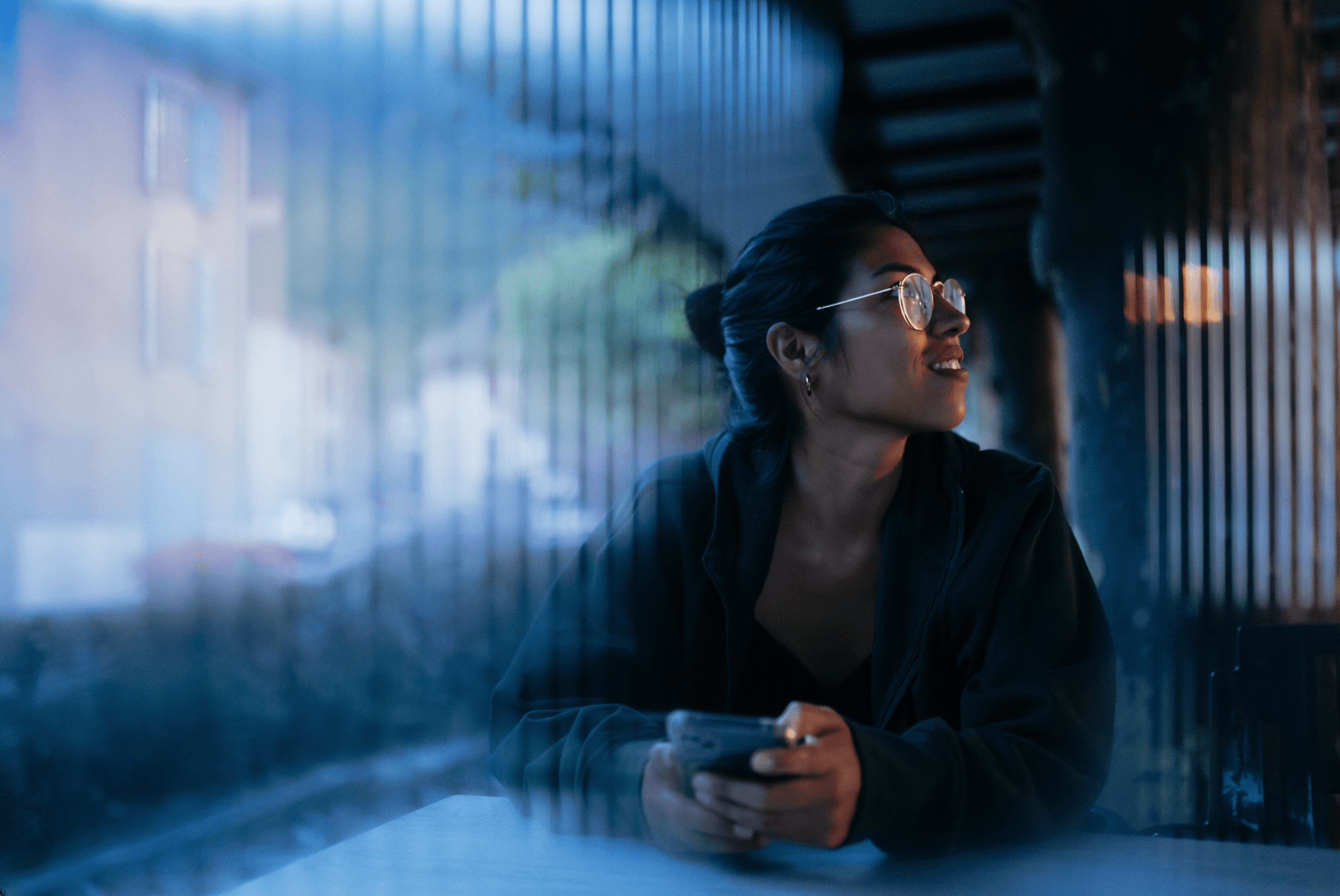 Woman with glasses looking away from mobile phone