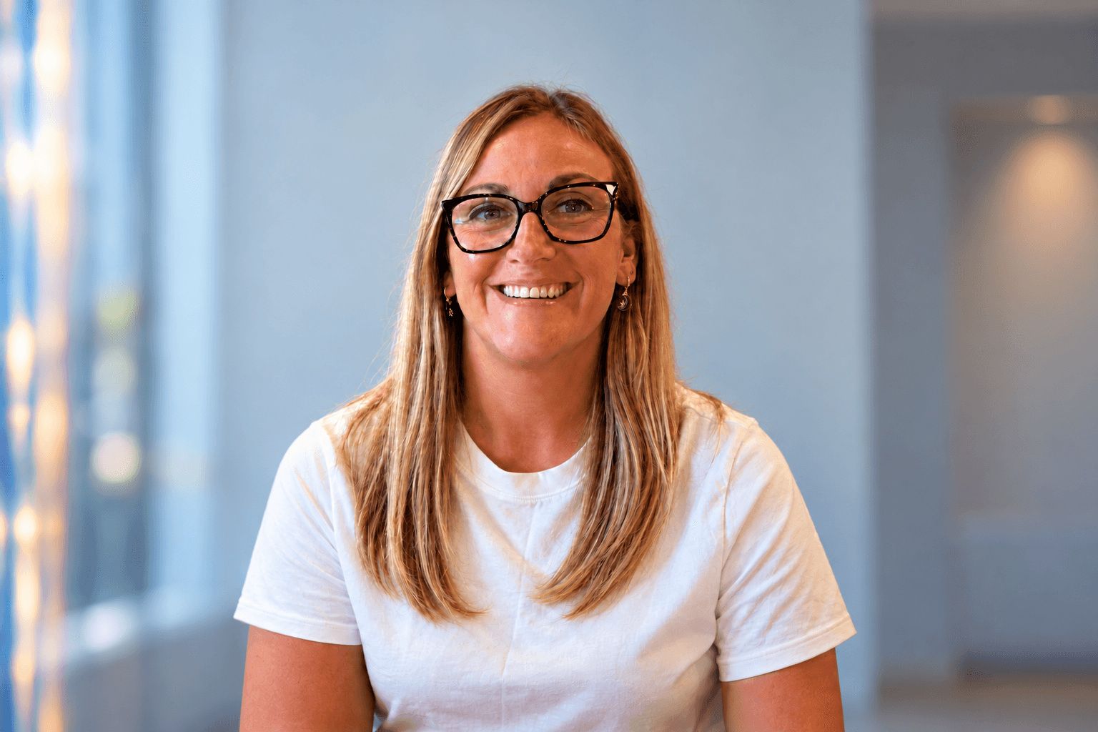 Blonde woman in glasses smiling in minimalist office